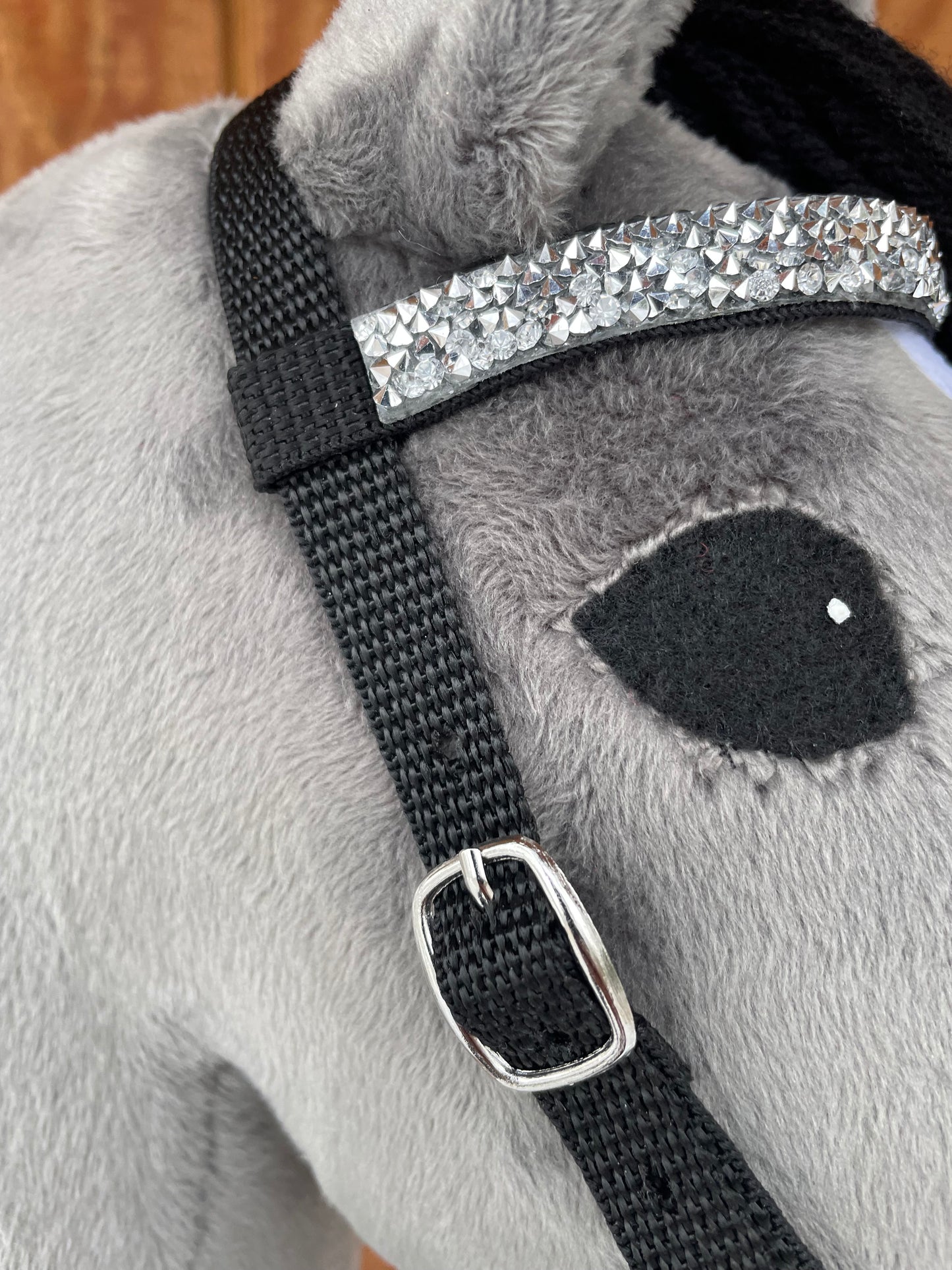 Close-up of a gray hobby horse's bridle on a wooden surface