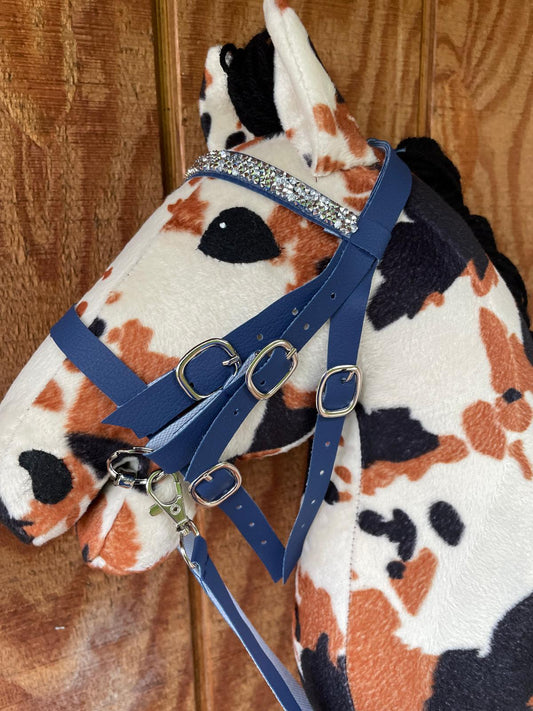 Plush hobby horse toy with a blue bridle on a wooden background