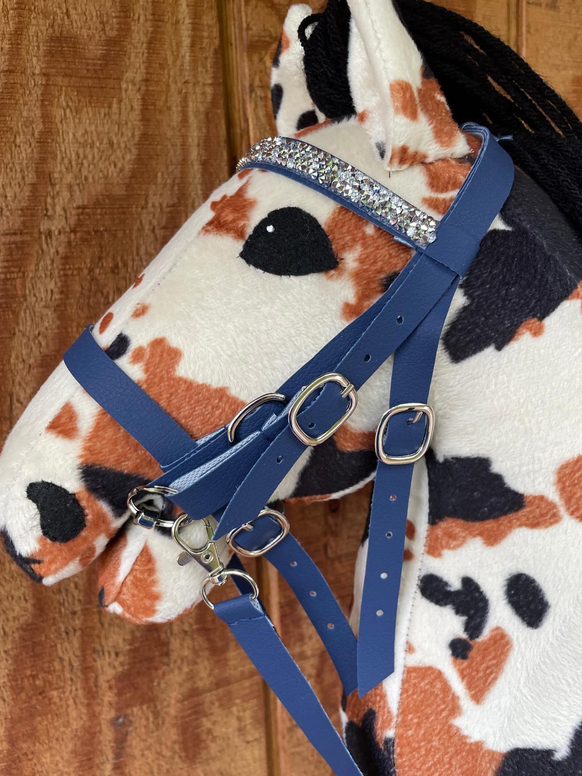 Hobby horse plush toy with a blue bridle on a wooden background