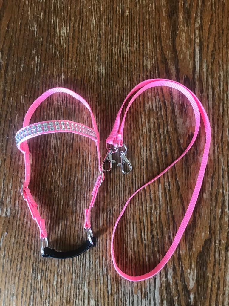 Pink hobby horse bridle with reins. the bridle has silver bling on the brow band