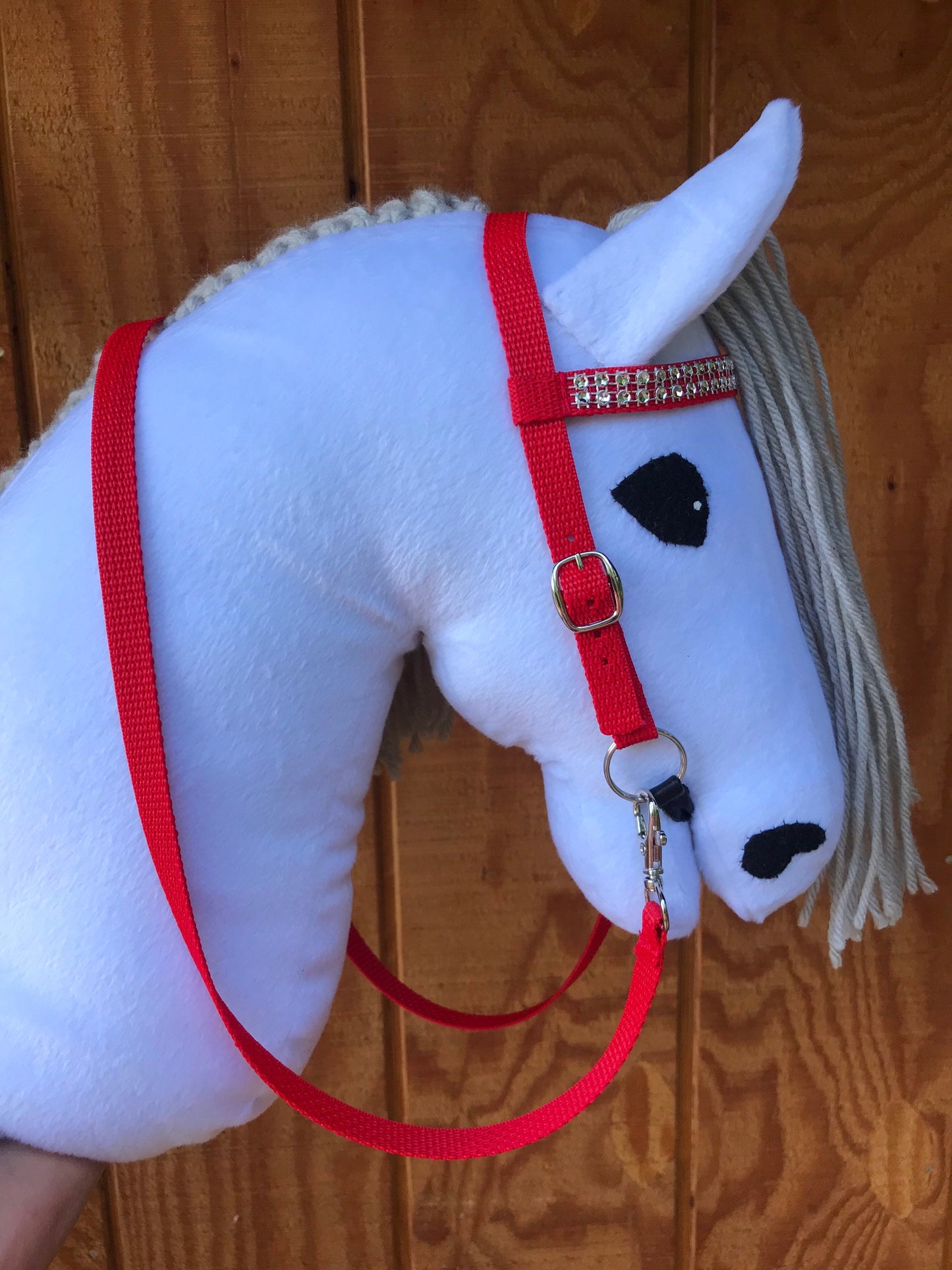 White Hobby horse wearign a bridle red with bling on the nose band