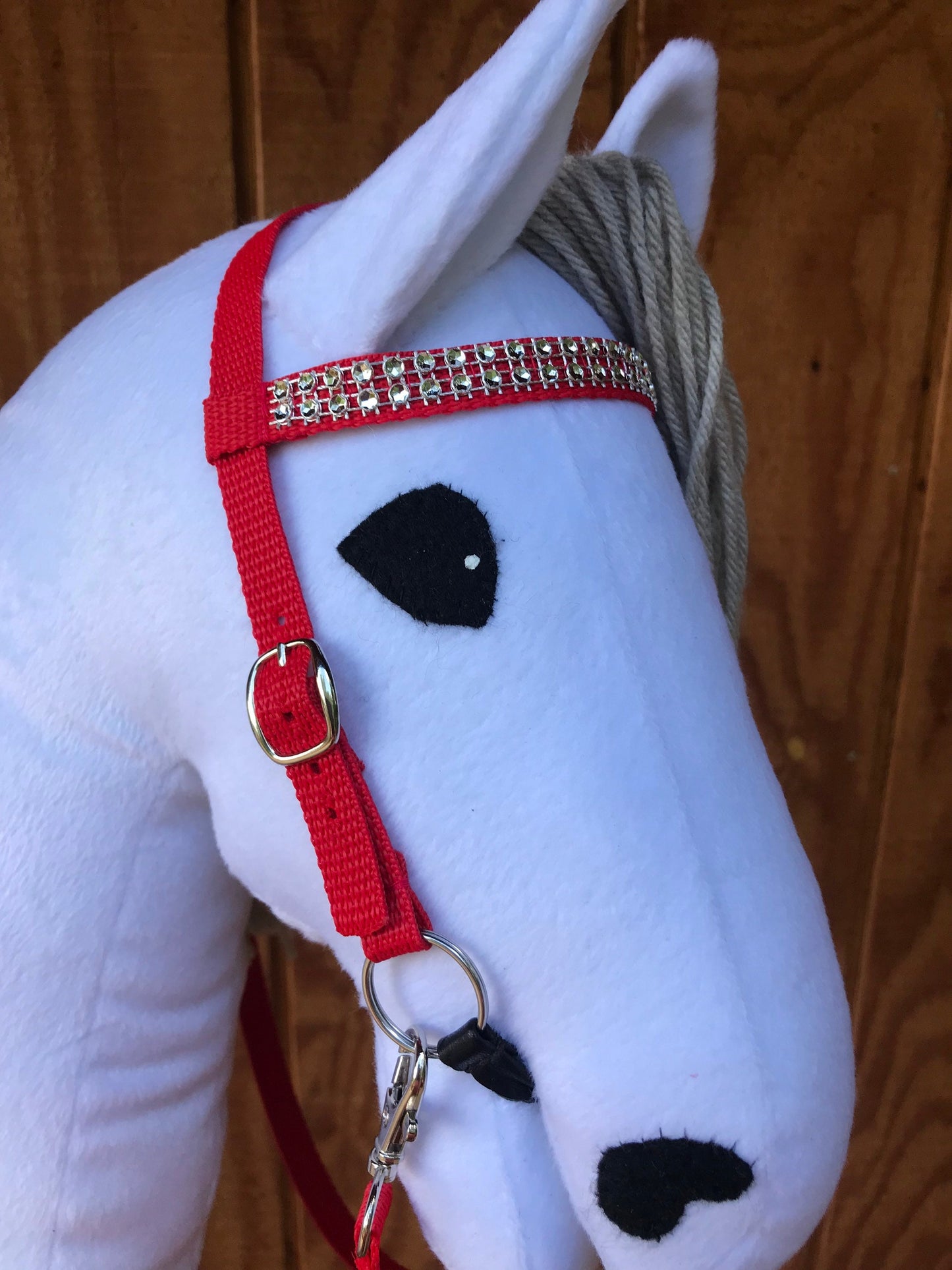White hobby horse wearing a bridle red with bling on a nose band