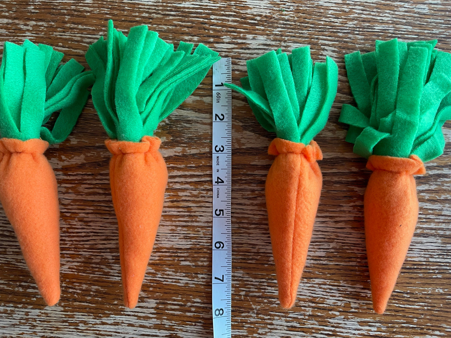 Hobby horse carrots on a wooden background, measuring tape next showing length 