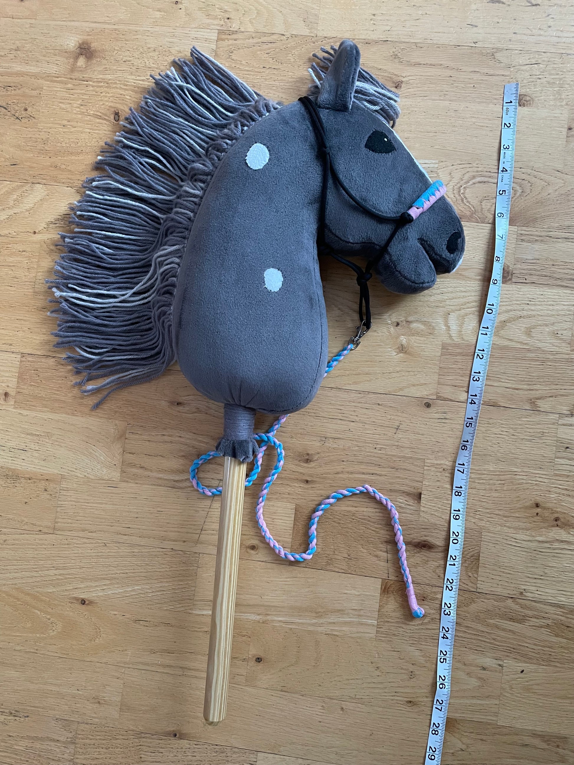 Hobby Horse dark gray with halter. Showing length of the horse with measuring tape. Wooden background.