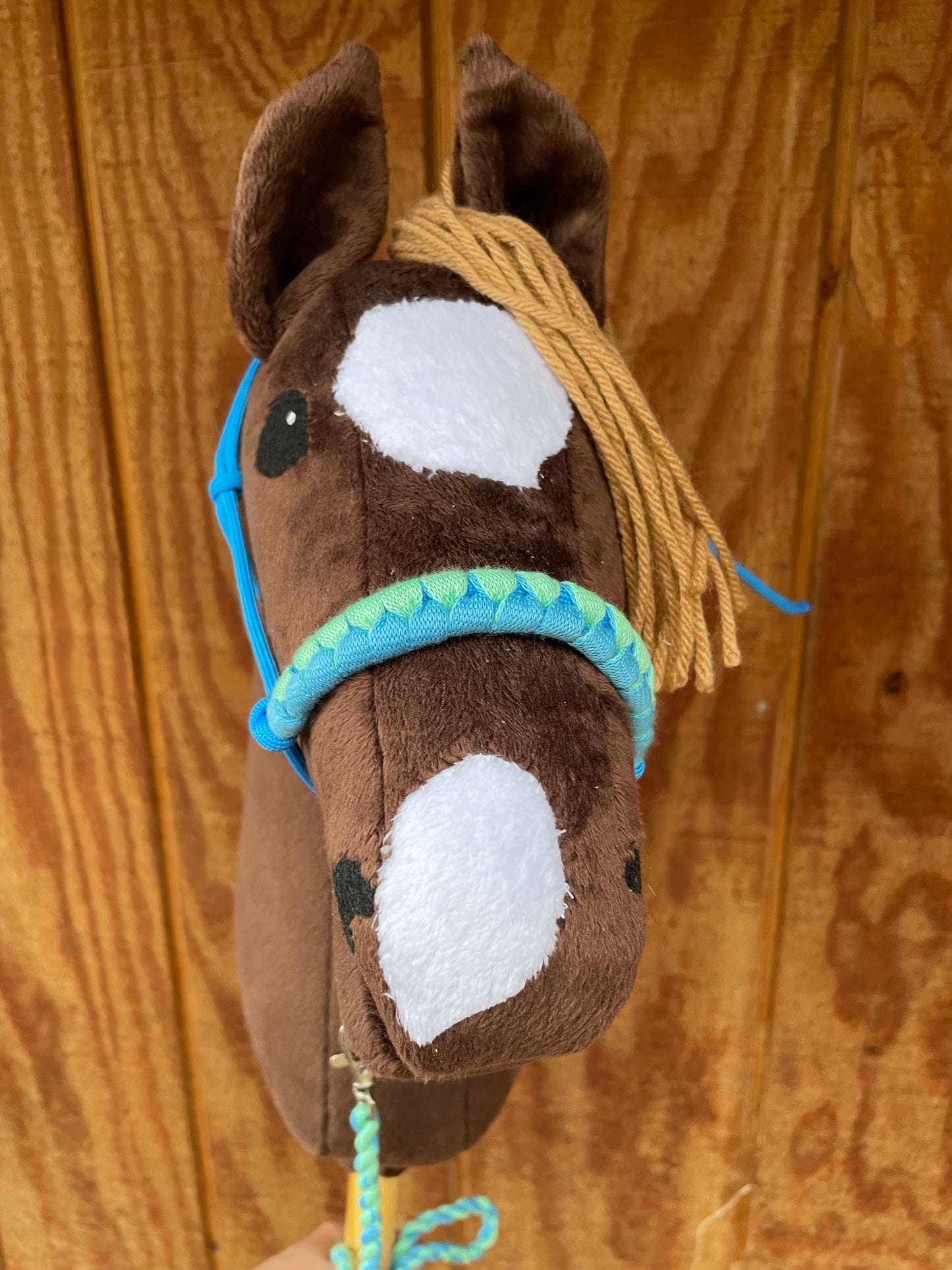 Brown plush toy hobby horse head with a brown mane on a wooden surface.