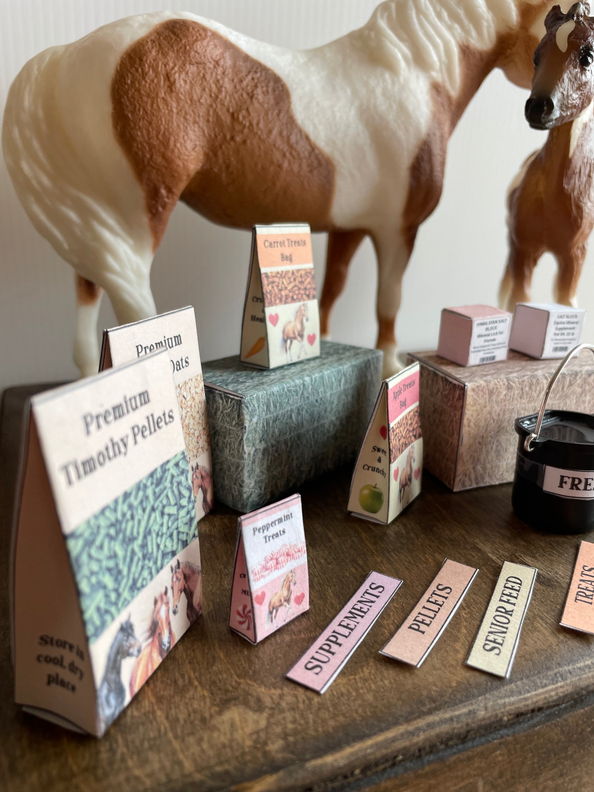 Box of miniature horse feed with labels on a wooden surface, 2 model horses on the background
