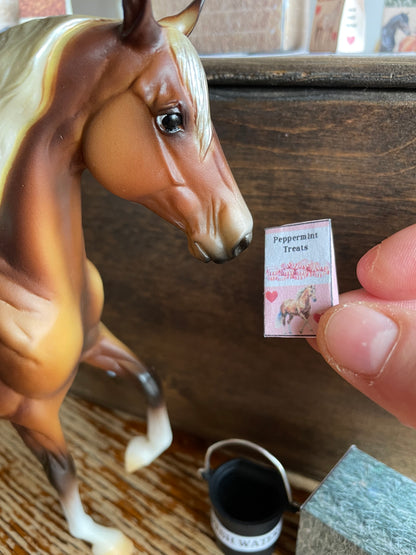 Close-up of a horse figurine with a hand holding a small product package.