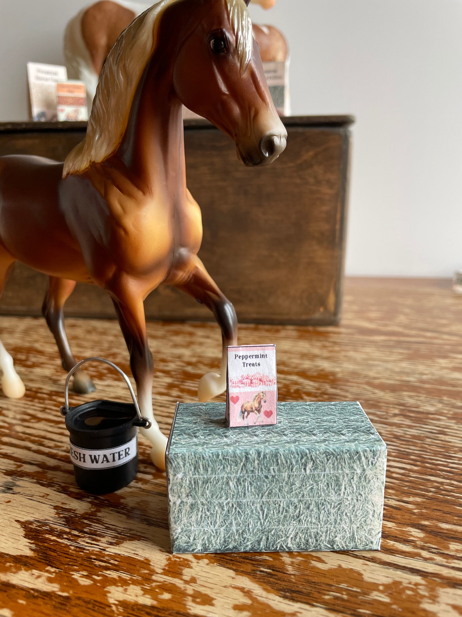 A horse and miniature hay bale and supplies on a wooden surface