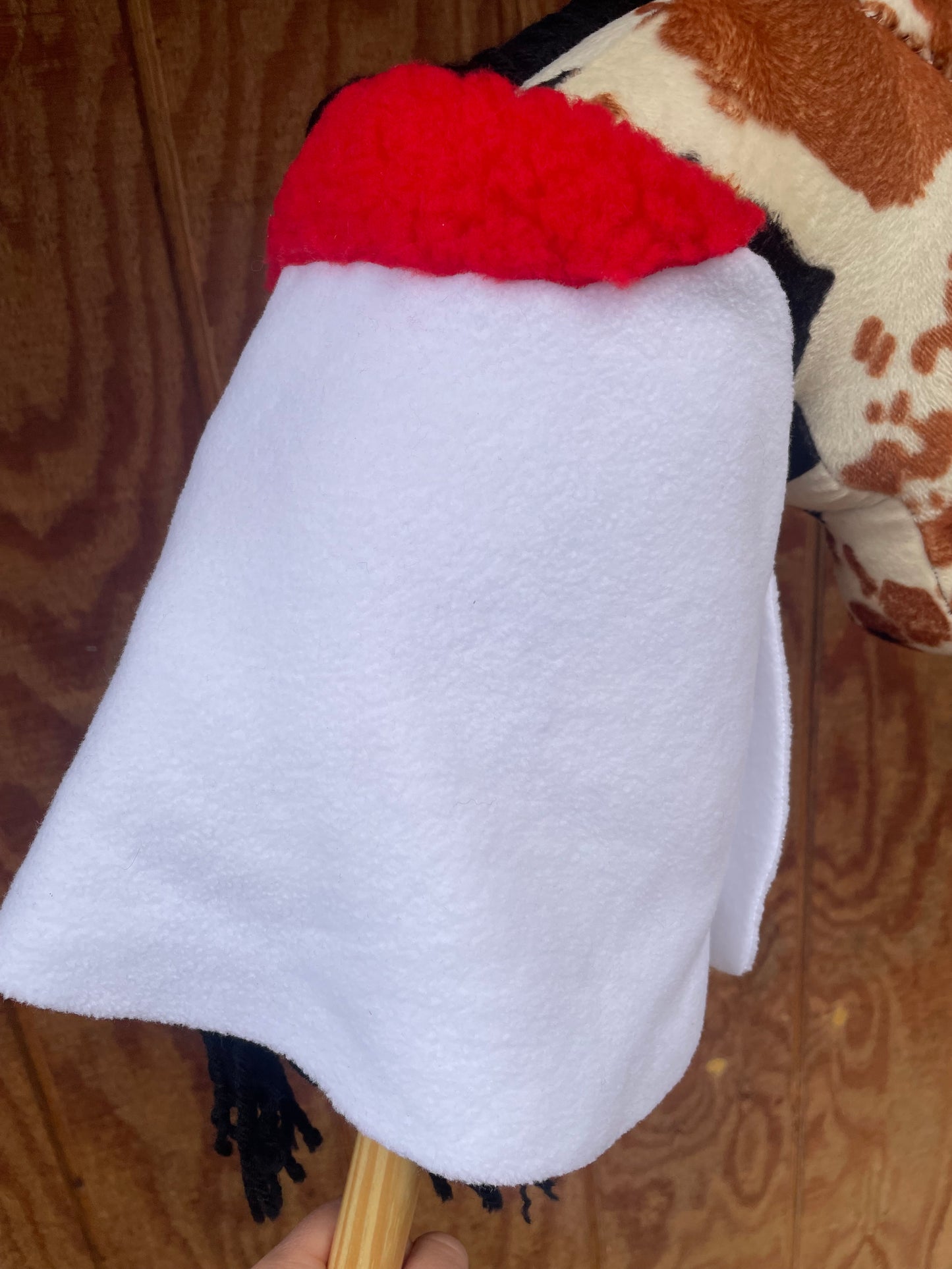 White hobby horse blanket with red padding on a wooden surface