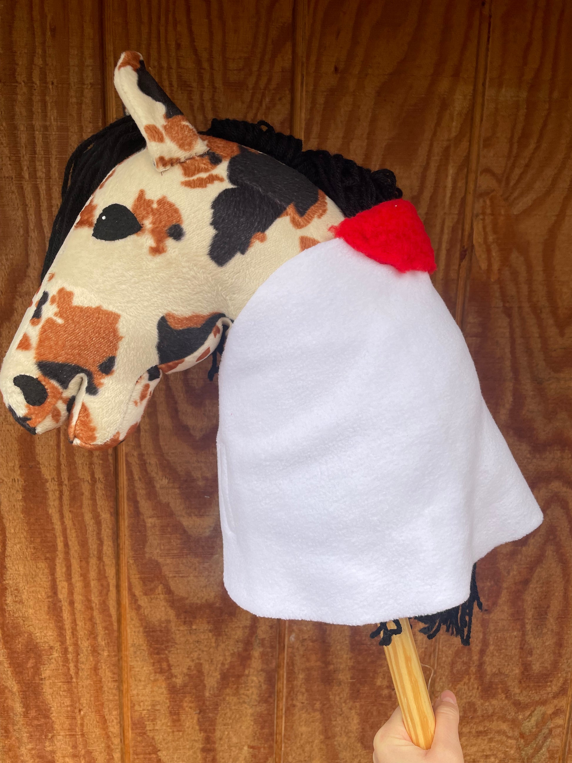 Hobby horse wearing a white blanket with a red padding on a wooden background