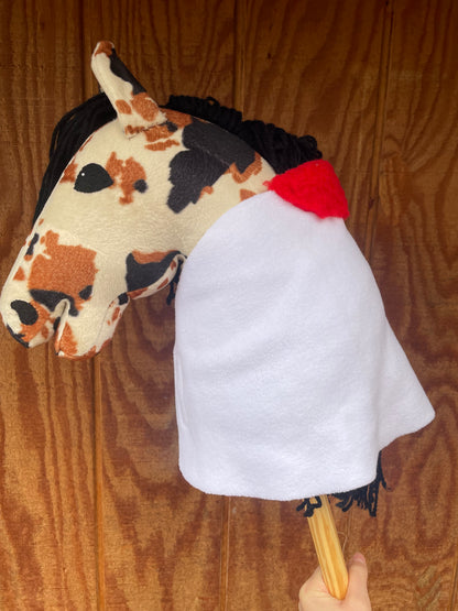 Hobby horse wearing a white blanket with a red padding on a wooden background
