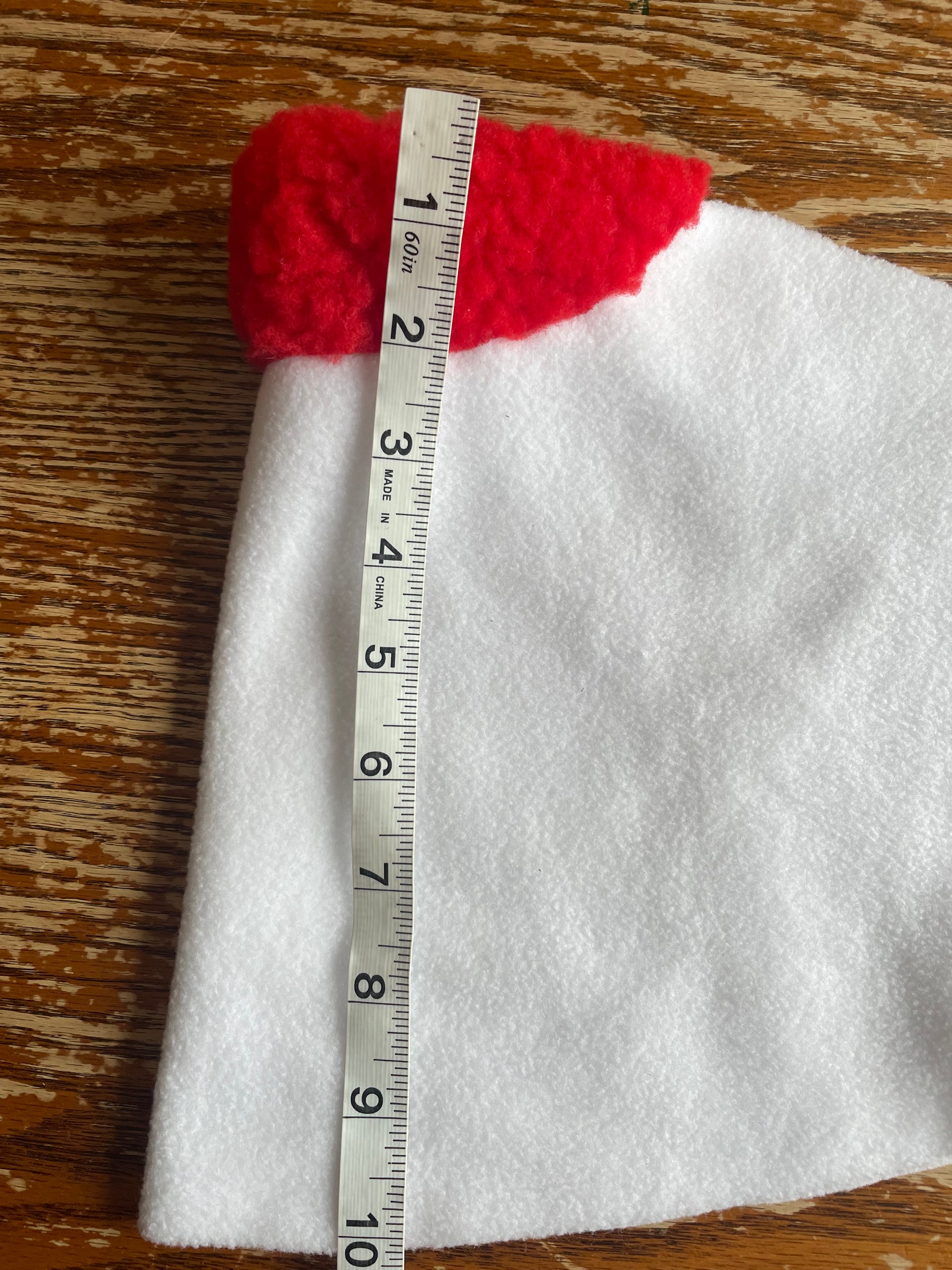 White hobby horse blanket with red padding with a measuring tape on a wooden surface
