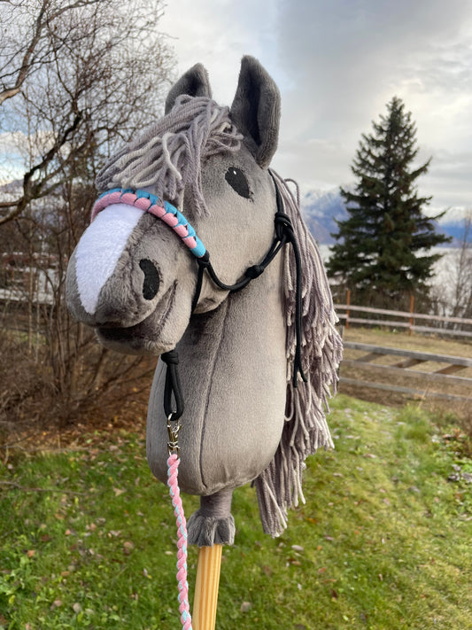 Plush toy gray hobby horse on a stick against a natural background, horse is wearing a halter.