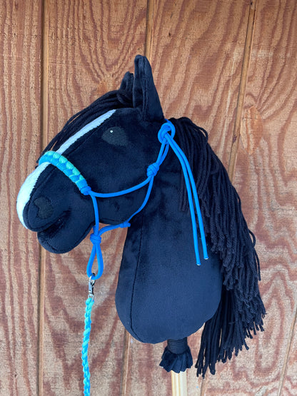Black hobby horse with blue halter on a wooden surface