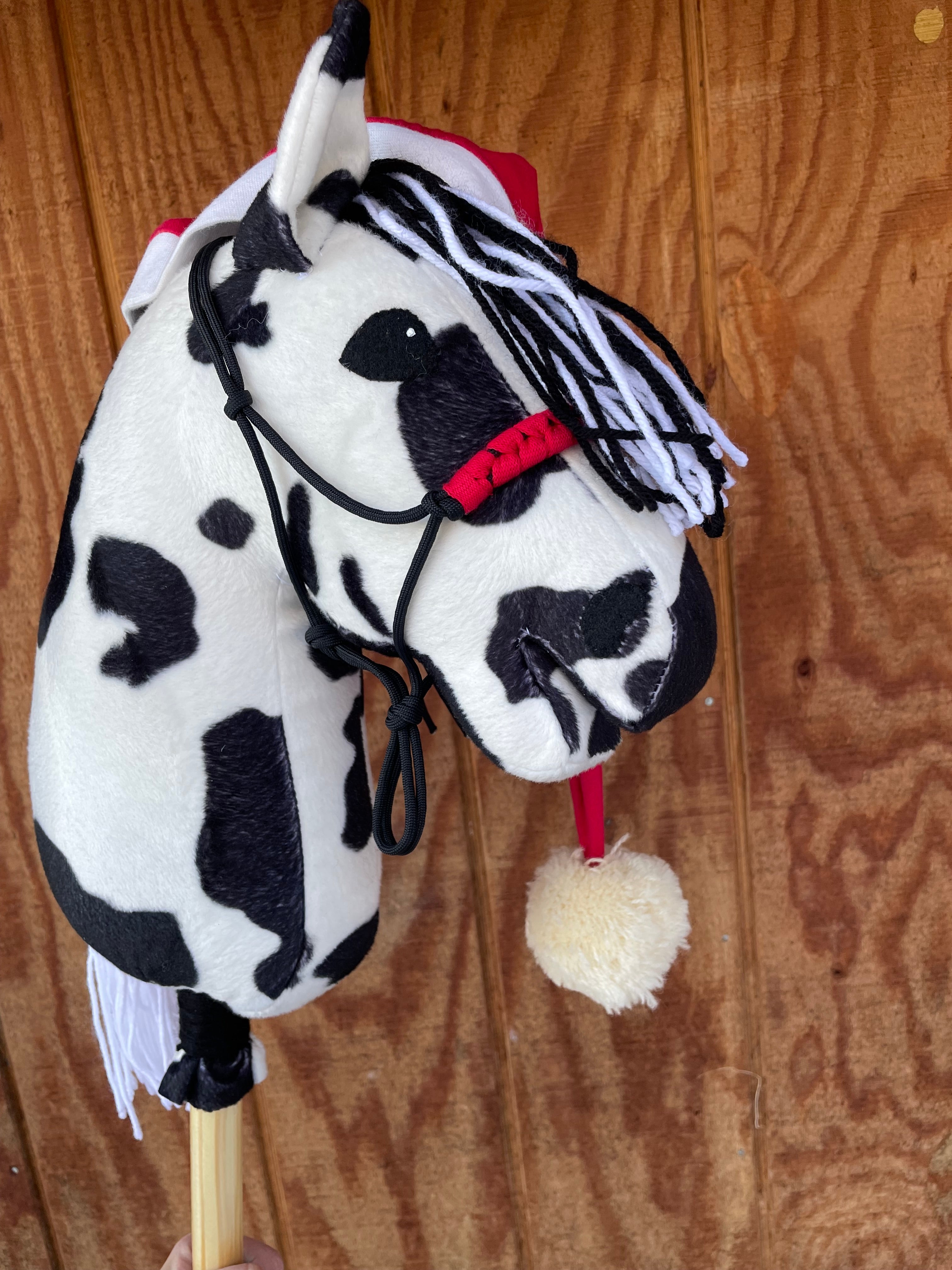 Pinto hobby horse black and white with Christmas hat against a wooden background