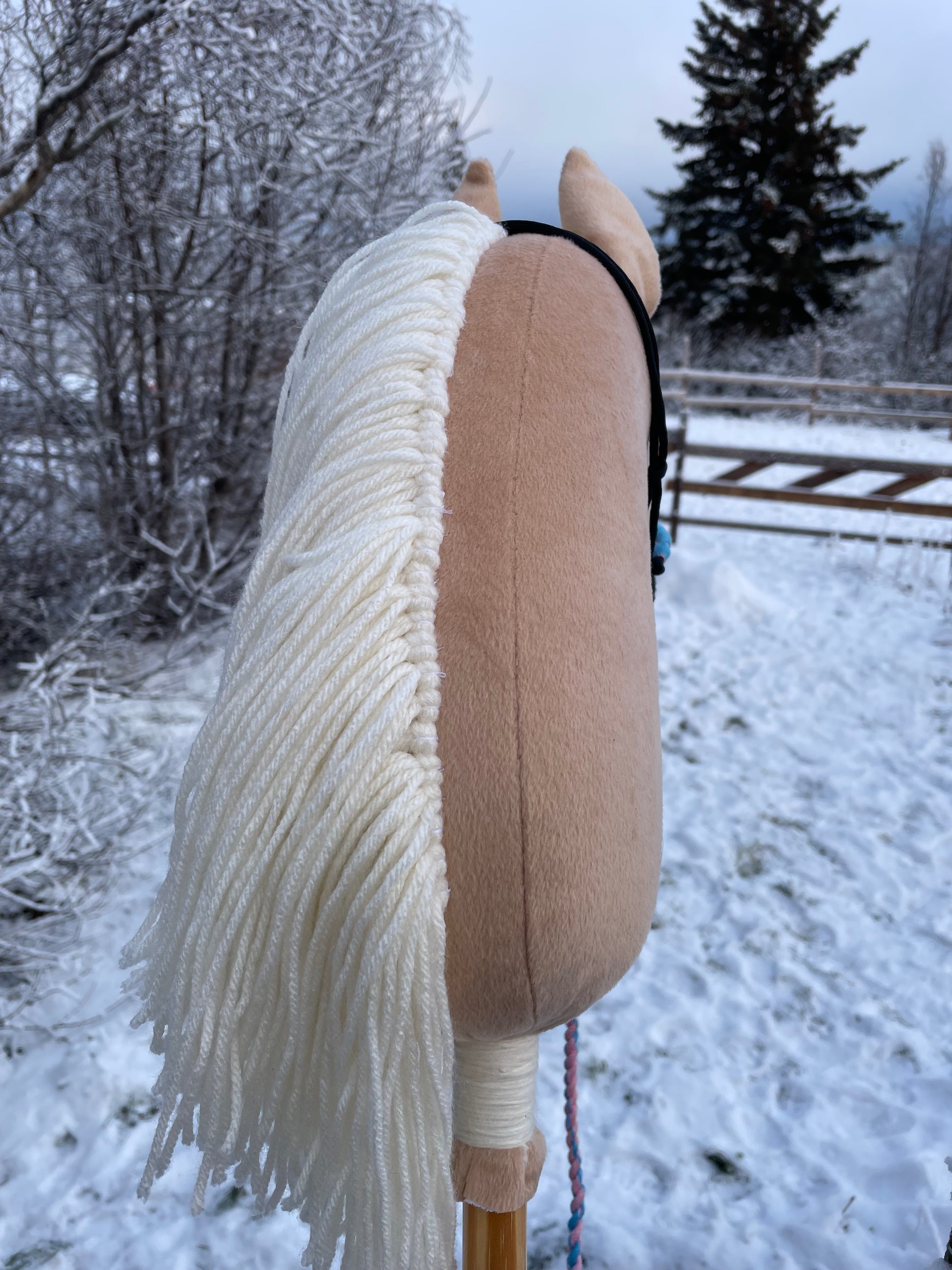 Plush hobby horse toy with a halter against a snowy background looking way