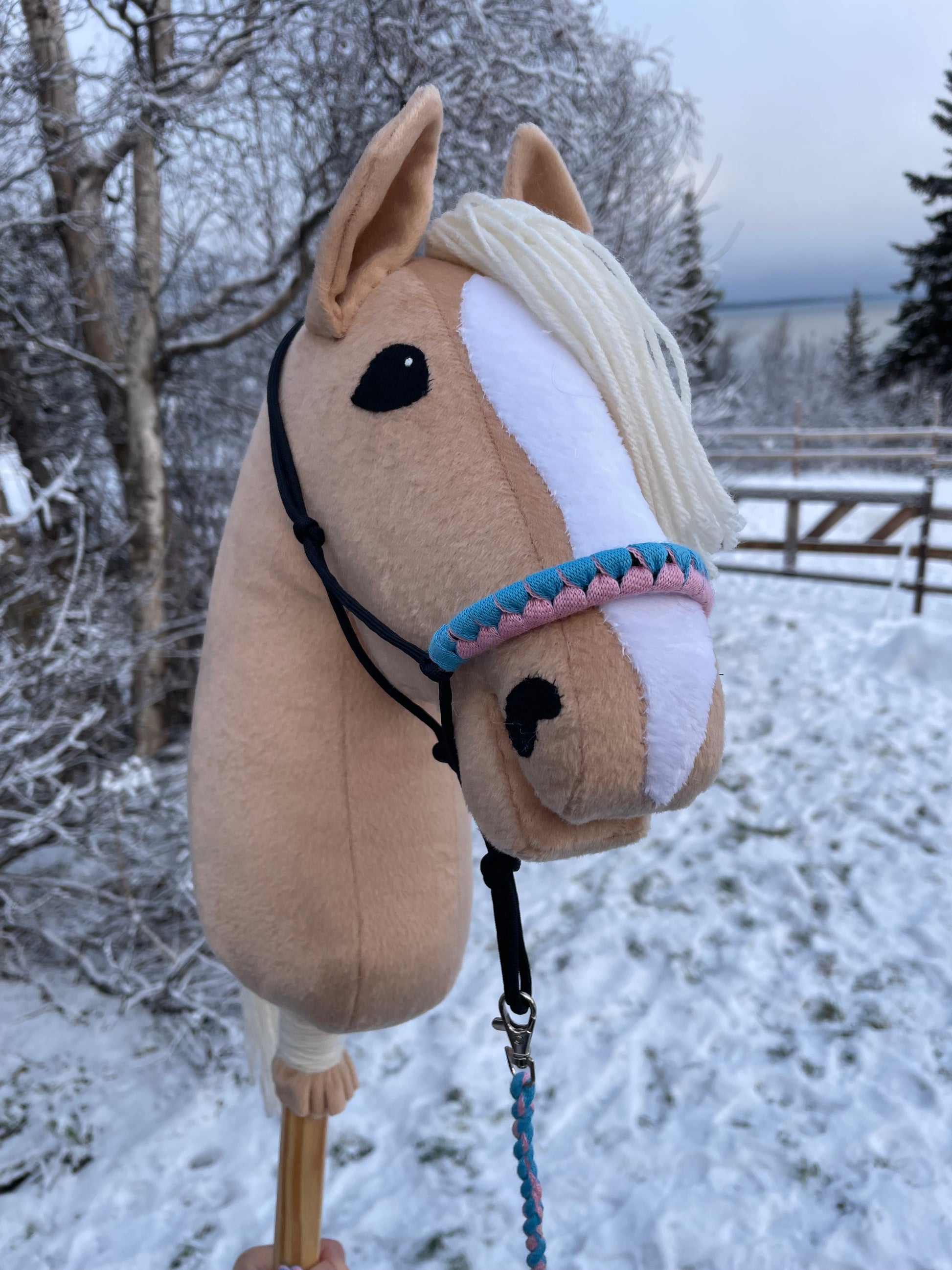 Plush hobby horse toy with a halter against a snowy background