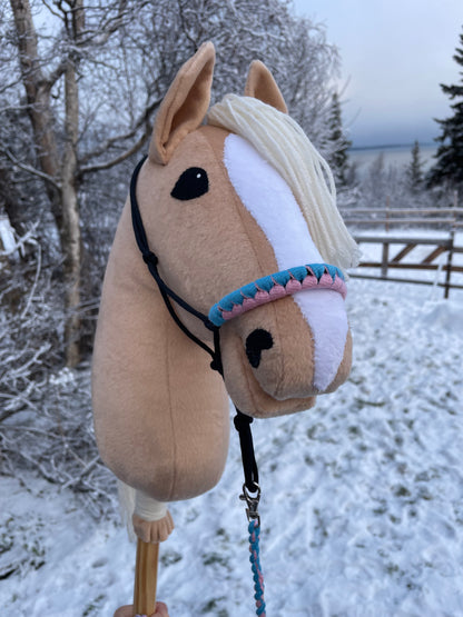 Plush hobby horse toy with a halter against a snowy background