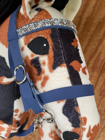 Close-up of a plush toy horse with a blue bridle and decorative elements.