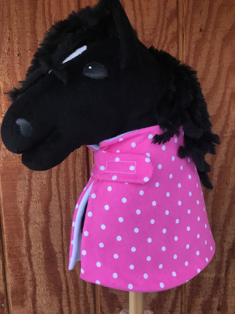 Hobby horse wearing a hot pink/red balnket with white dots on it