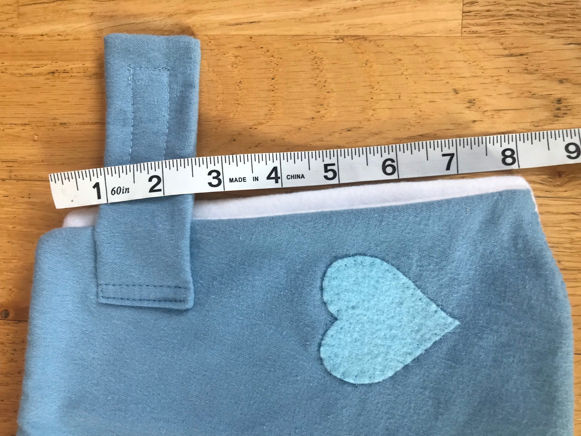 Hobby horse blanket light blue with blue hart on it and a measurement tape of 8"