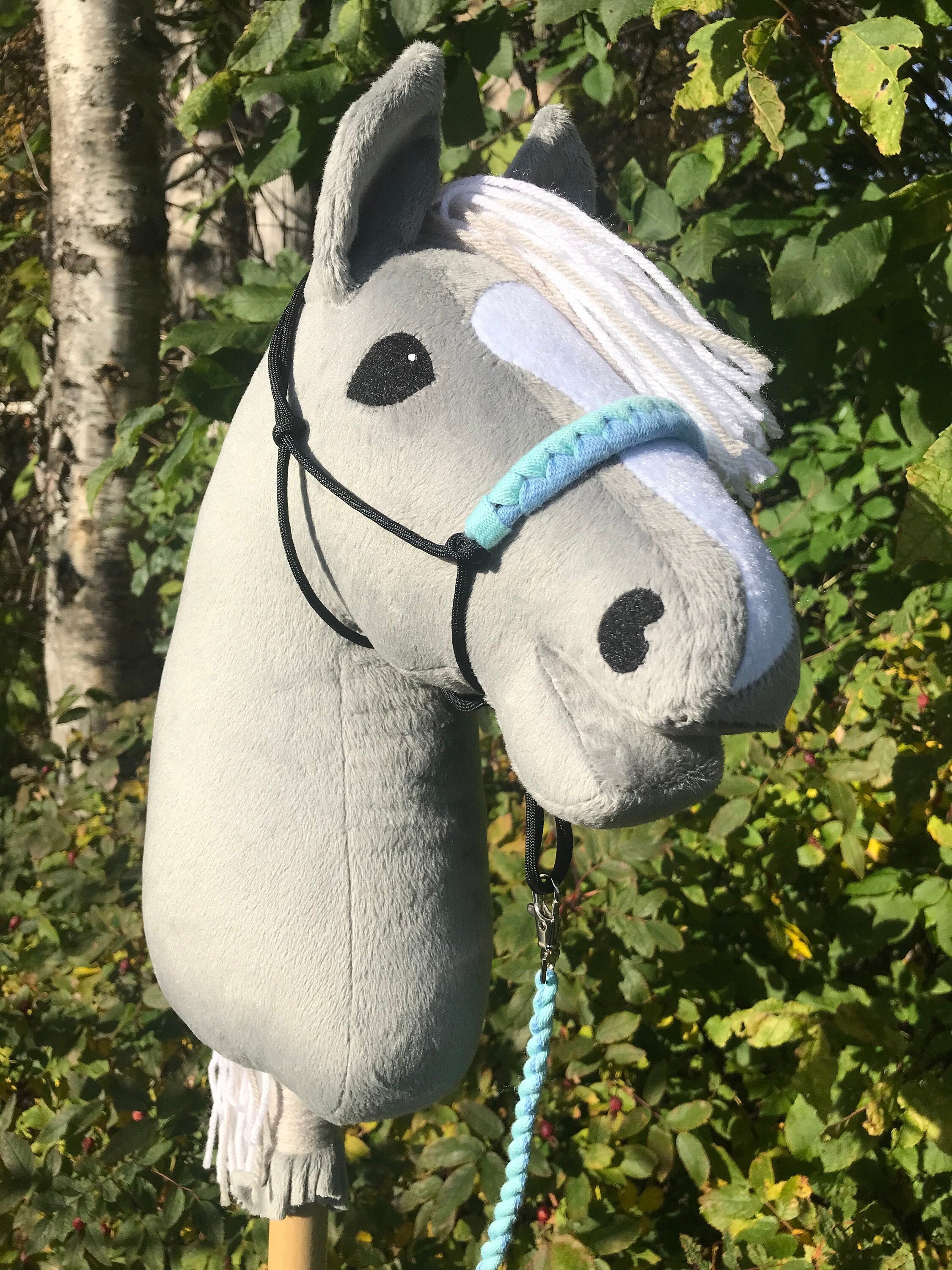 Hobby horse gray with rope halter, horse is outside on a sunny day