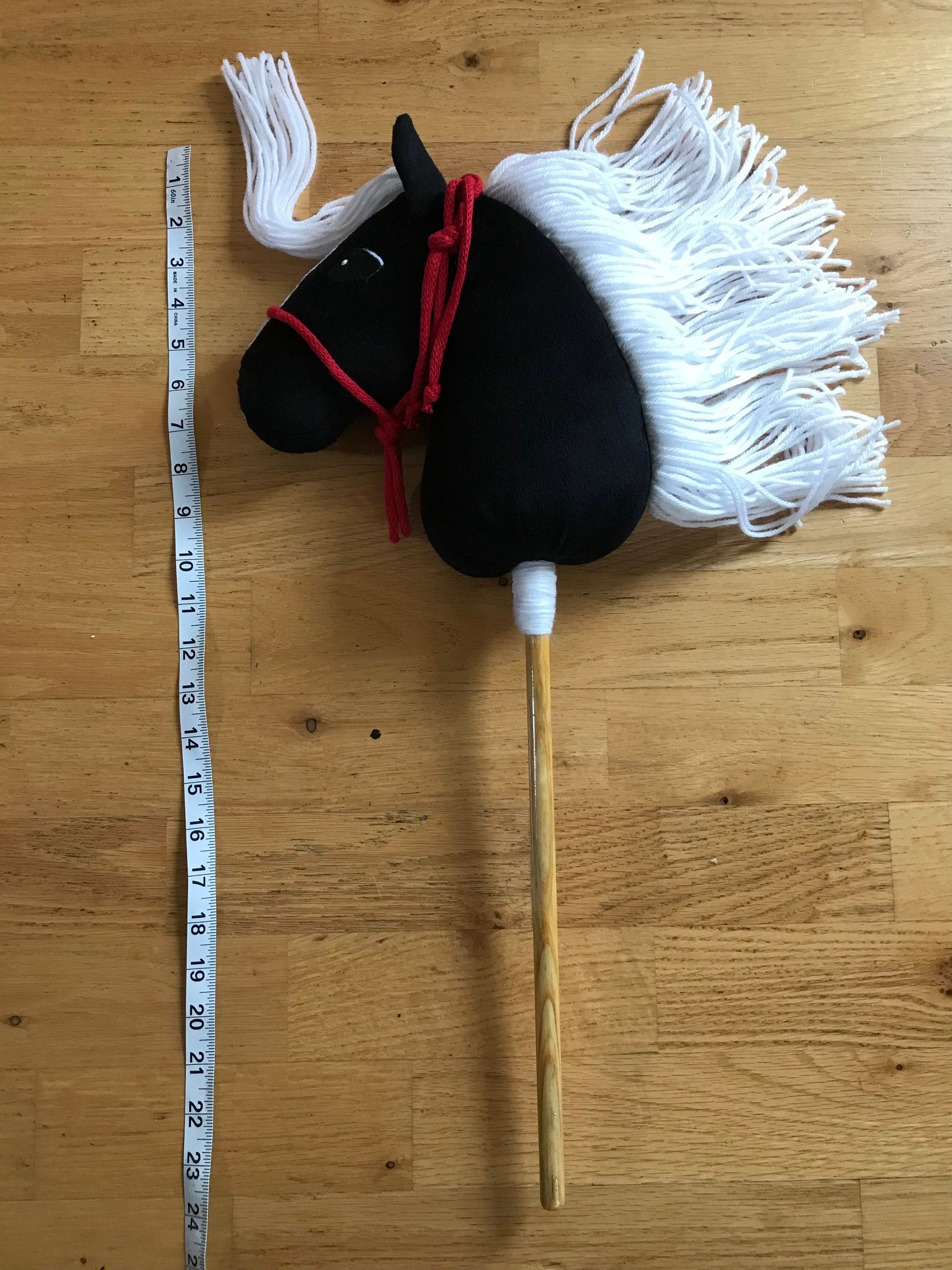 Hobby horse mini pony black on the floor next to measuring tape to show the length